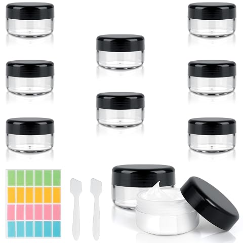Huit pots cosmétiques transparents avec deux spatules et 24 étiquettes, prêts à rejoindre une trousse de voyage.