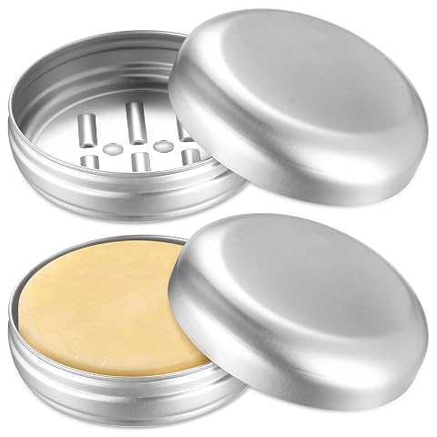 Deux boîtes rondes en aluminium pour savon, l’une ouverte avec un pain solide et l’autre fermée.