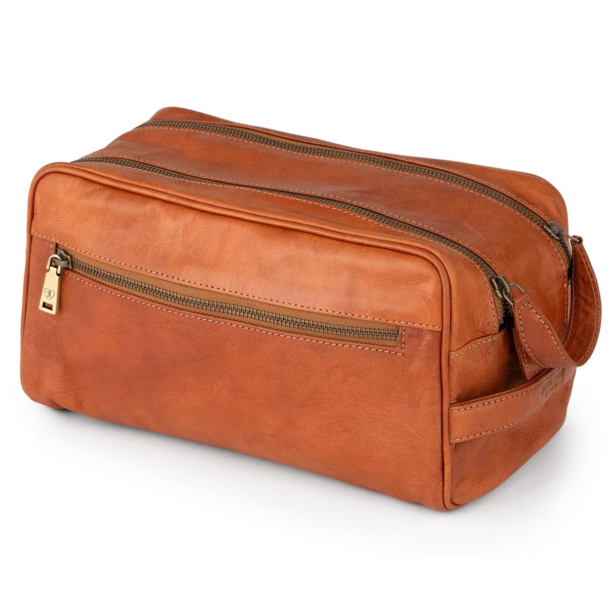 Trousse de toilette Tim en cuir marron avec poignée latérale, posée dans un décor de voyage sobre.