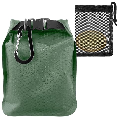 Sac à savon vert en nylon avec filet, bord roulé et mousqueton posé dans un décor de voyage