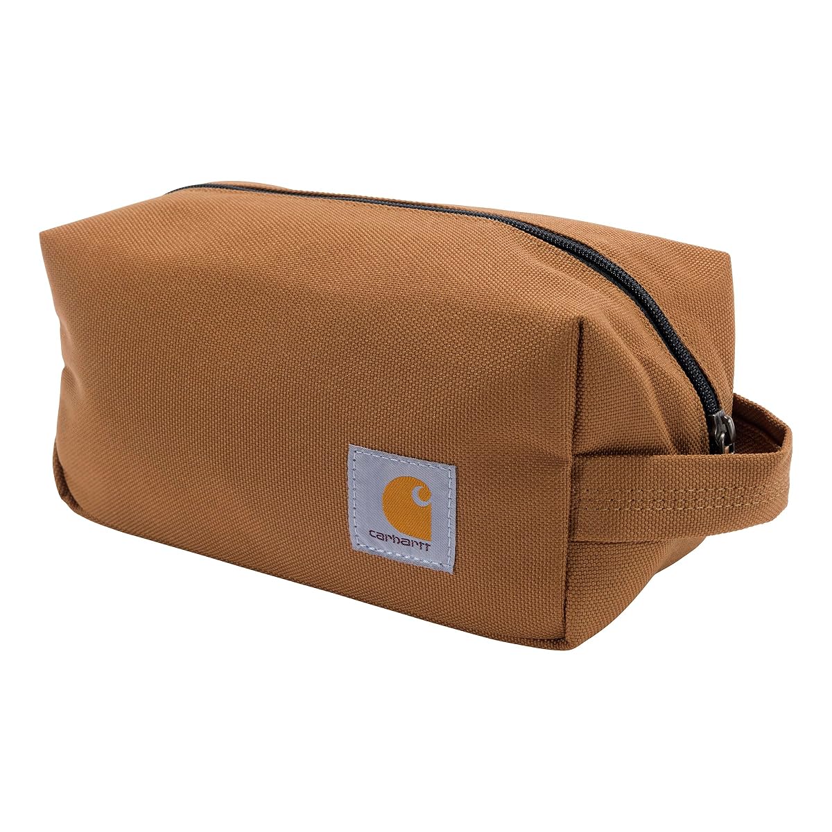 Trousse de toilette Carhartt brune en polyester avec poignée latérale, posée dans un décor de voyage sobre