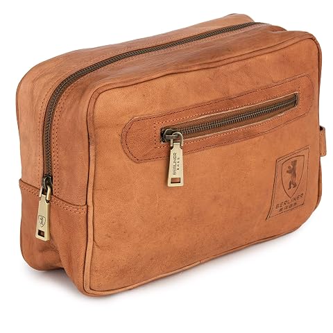 Trousse de toilette Paul en cuir marron avec poignée latérale, posée dans un décor de voyage sobre